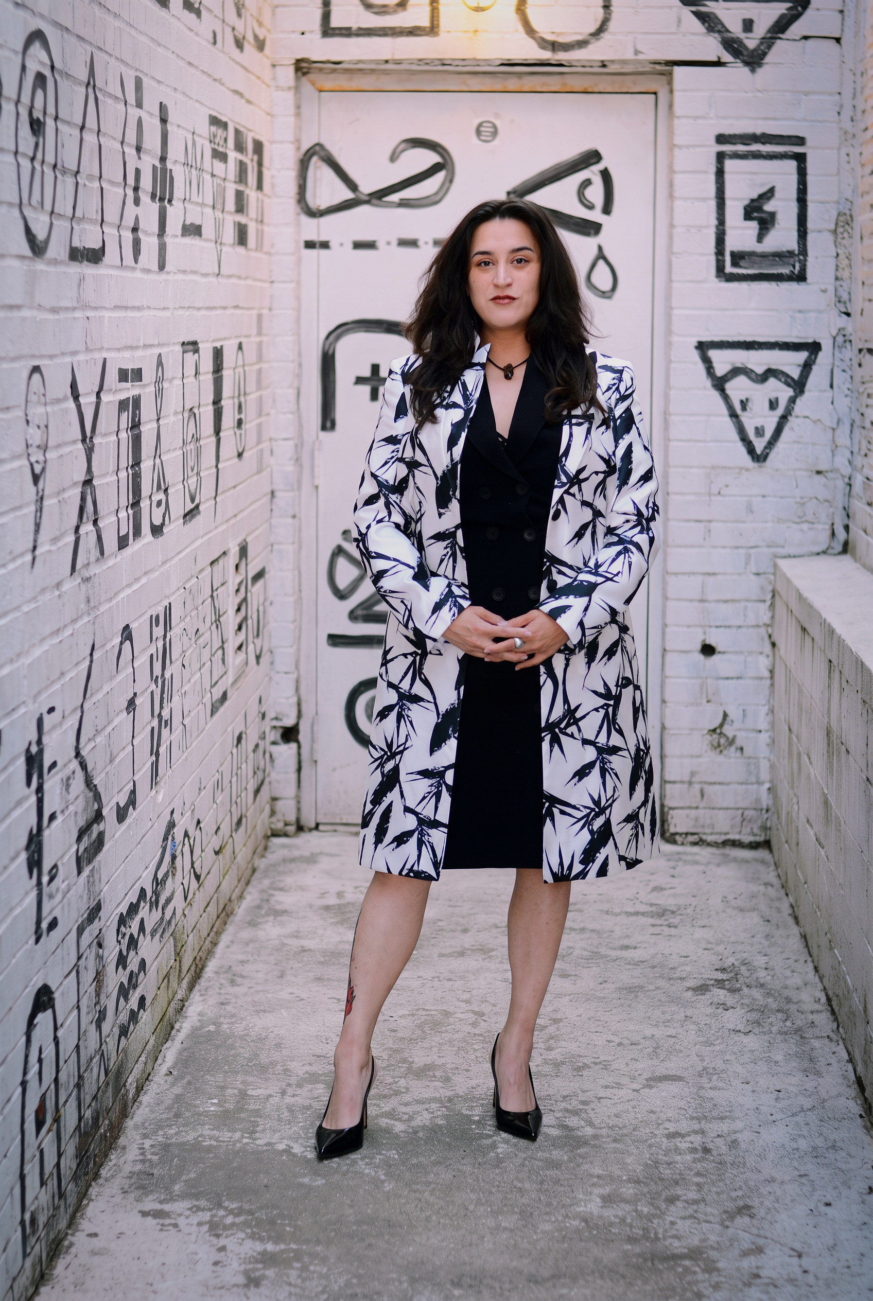 Lucinda Garcia, owner of Vesta Events, in a black and white patterned blazer against a painted brick wall